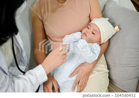 Close up view of adorable baby being checked by a doctor using a stethoscope. Close up view of adorable baby being checked by a doctor using a stethoscope. 104580452