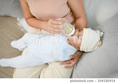 Portrait of cute newborn baby being fed by her mother using bottle. motherhood 104580454