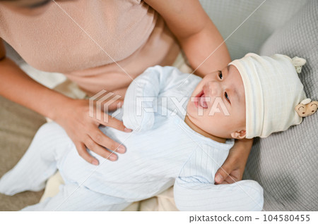 Close up view of baby being hold by mother while relaxing on the sofa 104580455