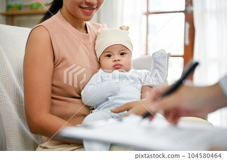 Adorable newborn baby is being diagnose by doctor in the living room. Adorable newborn baby is being diagnose by doctor in the living room. 104580464
