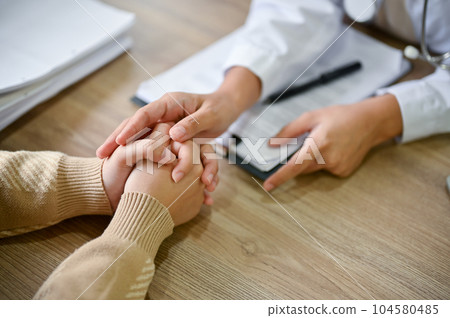 Close up view of doctor touching patient hand, showing empty and kindness. 104580485