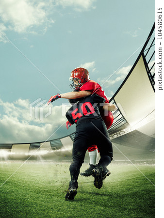 Tense game. Competitive, motivated sportsmen, american football players in motion playing, running at 3D stadium on sunny day Tense game. Competitive, motivated sportsmen, american football players in motion playing, running at 3D stadium on sunny day 104580615