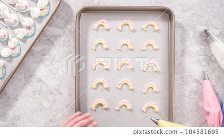 Flat lay. Step by step. Piping meringue mix into unicorn-shaped pops on a baking sheet lined with parchment paper. Flat lay. Step by step. Piping meringue mix into unicorn-shaped pops on a baking sheet lined with parchment paper. 104581695