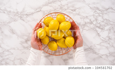 Flat lay. Step by step. Fresh organic lemons in a wire basket on a marble surface. 104581702