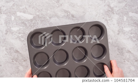 Flat lay. Step by step. Lining cupcake baking pan with foil cupcake liners to bake unicorn rainbow chocolate cupcakes. 104581704