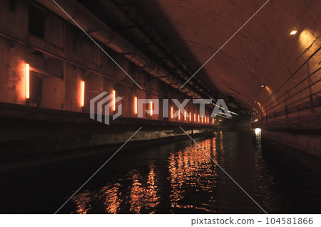 Illuminated concrete tunnel with water. Abandoned underground submarine base Illuminated concrete tunnel with water. Abandoned underground submarine base 104581866