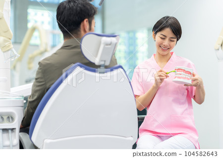 Dental hygienist treating a patient 104582643