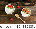 Strawberry yogurt in a wooden bowl with granola, mint and fresh strawberry on wooden background. Health food concept 104582861