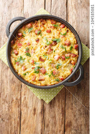 German potato pancake Dibbelabbes with bacon and leek close-up in a frying pan. Vertical top view German potato pancake Dibbelabbes with bacon and leek close-up in a frying pan. Vertical top view 104585081