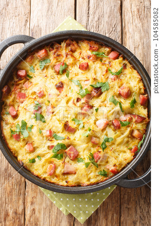 Dibbelabbes is an oven baked potato leek hash, prepared from grated raw potatoes, bacon and leeks close-up in a pan. Vertical top view Dibbelabbes is an oven baked potato leek hash, prepared from grated raw potatoes, bacon and leeks close-up in a pan. Vertical top view 104585082