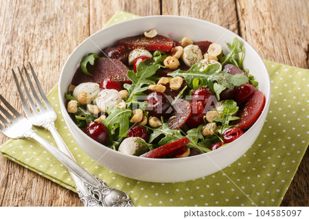 Dietary vegetable berry salad of arugula, beets, cherry berries, cheese, hazelnuts close-up in a bowl. Horizontal Dietary vegetable berry salad of arugula, beets, cherry berries, cheese, hazelnuts close-up in a bowl. Horizontal 104585097