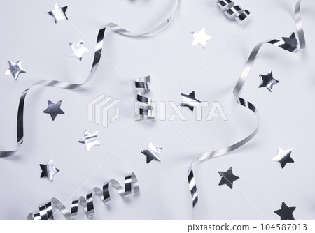 White background with a silver serpentine and stars. concept of celebrating a birthday,newborn , party or anniversary in silver tones. High quality photo 104587013