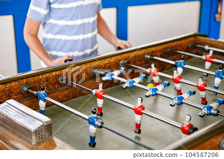 Close-up of kid boy playing table soccer. Happy excited child having fun with family game with siblings or friends. Positive kid. Close-up of kid boy playing table soccer. Happy excited child having fun with family game with siblings or friends. Positive kid. 104587206