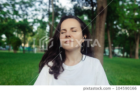 Solo yoga in park. Woman is engaged in meditation in the lotus position. Relaxation of the nervous system. Self-help in unloading the nervous system. Serenity and recovery 104590166