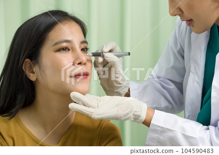 Facial plastic surgery concept. Middle aged woman on consultation at surgeon, doctor making marks on female patient's face. Close up Facial plastic surgery concept. Middle aged woman on consultation at surgeon, doctor making marks on female patient's face. Close up 104590483