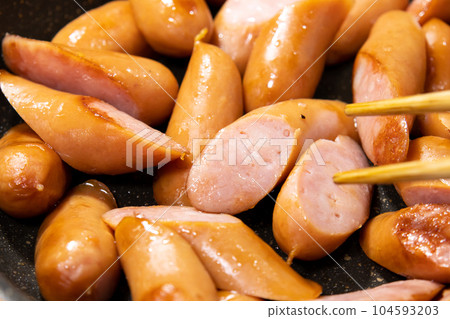 A cooking scene where diagonally cut wiener sausages are fried in a frying pan. A cooking scene where diagonally cut wiener sausages are fried in a frying pan. 104593203