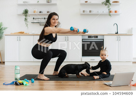 Female parent exercising near infant with Dachshund at home 104594609