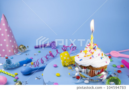 Birthday cake or cupcake with a burning candle on a blue background. Party, birthday or anniversary celebration concept with place for text, copy space. High quality photo 104594783