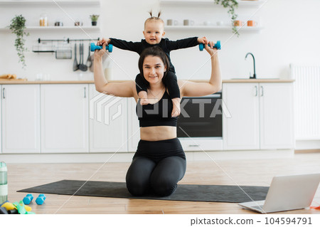 Mom carrying baby with dumbbells on shoulders while sitting Mom carrying baby with dumbbells on shoulders while sitting 104594791