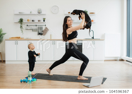 Female with dog standing in asana near baby girl at home 104596367