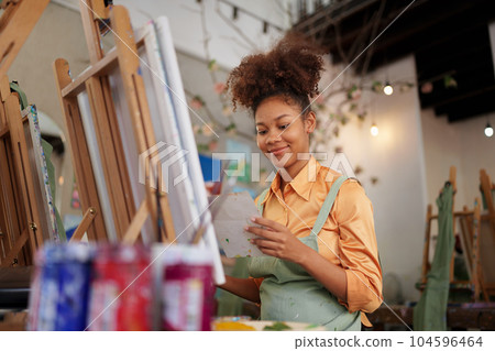 Beautiful American African artist woman painting in art studio at the university classroom Beautiful American African artist woman painting in art studio at the university classroom 104596464