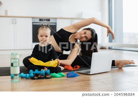 Mom doing side bends while child checking band on floor Mom doing side bends while child checking band on floor 104596884
