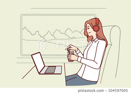 Woman train passenger uses laptop working on trip and drinks coffee sitting near large window 104597005