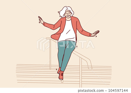 Elderly woman slides down stair railing having fun and being active after retirement 104597144