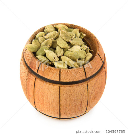 Cardamom in a wooden bowl isolated on white. Cardamom in a wooden bowl isolated on white. 104597765