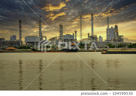 An oil refinery located on the Chao Phraya River, in Bangkok, Thailand, a large industrial factory. and the golden evening sky Big clouds when it's about to rain An oil refinery located on the Chao Phraya River, in Bangkok, Thailand, a large industrial factory. and the golden evening sky Big clouds when it's about to rain 104599530