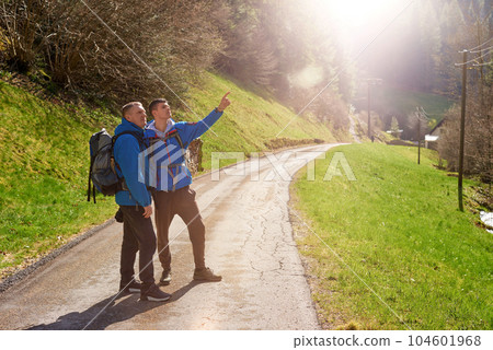 Two hikers are in the mountains in the spring nature outdoor. Hiking with backpacks. Two friends travel together in picturesque places. The man shows the way. Two men on a hiking trip in the mountains 104601968
