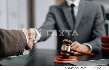 Lawyer shaking hands with client after discussing final contract agreement. 104602106