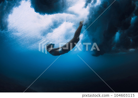 Surfer girl dive underwater with ocean powerful and dangerous wave. 104603115