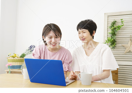 mother and daughter using laptop at home 104604501