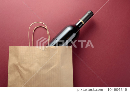 Paper shopping bag with a bottle of red wine. 104604846