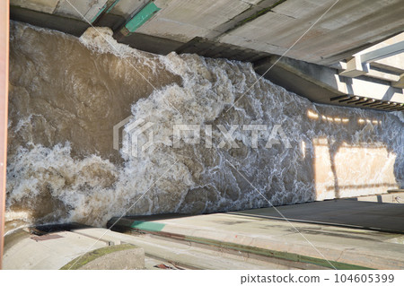 A muddy river with a brown and swollen water after the rain 104605399