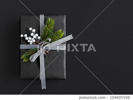 Black gift box with ribbon, spruce branches and silver berries with copyspace 104605598