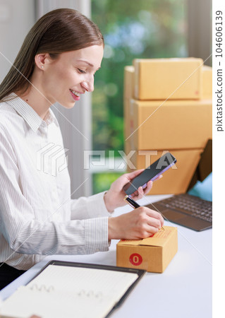 Concept of parcel delivery and selling online,Retailer writing customer detail on parcel box and prepare to send product parcel to the customer 104606139