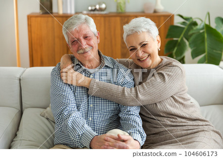 Senior adult mature couple hugging at home. Mid age old husband and wife embracing with tenderness love enjoying sweet bonding wellbeing. Grandmother grandfather together. Family moment love and care Senior adult mature couple hugging at home. Mid age old husband and wife embracing with tenderness love enjoying sweet bonding wellbeing. Grandmother grandfather together. Family moment love and care 104606173