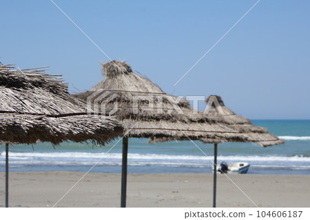 Mediterranean sand beach. Three straw umbrellas. Selective focus Mediterranean sand beach. Three straw umbrellas. Selective focus 104606187