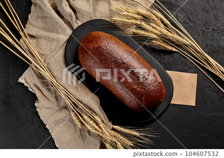Whole rye bread with ears of wheat, burlap and piece of craft paper 104607532