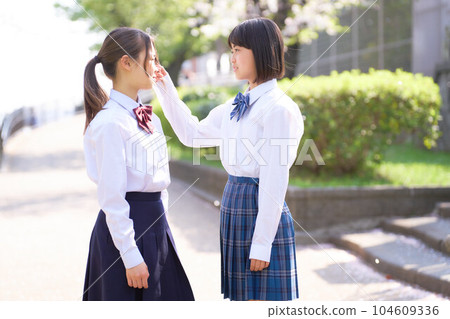 Two junior high school girls talking while looking at each other's faces, school uniform, school life Two junior high school girls talking while looking at each other's faces, school uniform, school life 104609336