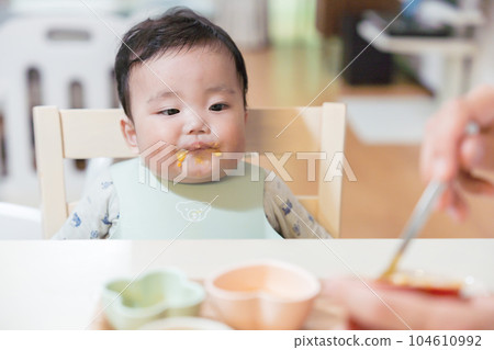 8 months old baby staring and waiting for daddy to feed him baby food 104610992
