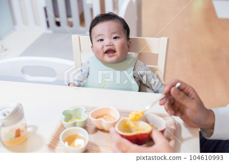 An 8-month-old baby with a happy smile after being fed baby food by his dad 104610993