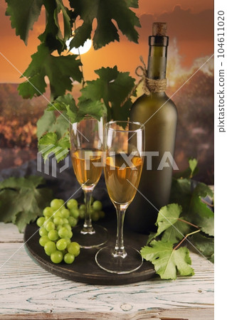 Wine glasses, bunches of grapes on a wooden table, on the background of the sunset, romantic atmosphere, harvest, organic natural products Wine glasses, bunches of grapes on a wooden table, on the background of the sunset, romantic atmosphere, harvest, organic natural products 104611020