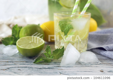 Fresh mojito drink made of lemon, lime, ice and mint leaves, mojito ingredients on a light background, cold seasonal drinks Fresh mojito drink made of lemon, lime, ice and mint leaves, mojito ingredients on a light background, cold seasonal drinks 104611096