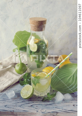 Fresh mojito drink made of lemon, lime, ice and mint leaves, mojito ingredients on a light background, cold seasonal drinks Fresh mojito drink made of lemon, lime, ice and mint leaves, mojito ingredients on a light background, cold seasonal drinks 104611097