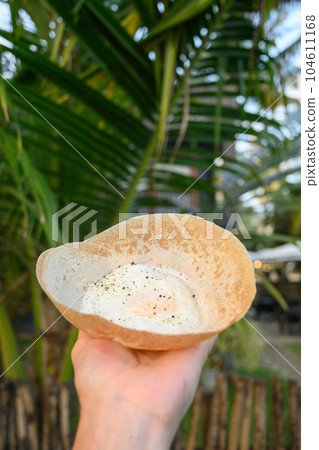 Sri lankan street food egg hopper in woman's hand. 104611168
