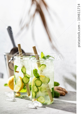 Summer refreshing or detox drinks, lemon cucumber mint infused water, hard light and shadows. Summer refreshing beverage, drink with trendy zero waste accessories Summer refreshing or detox drinks, lemon cucumber mint infused water, hard light and shadows. Summer refreshing beverage, drink with trendy zero waste accessories 104611714