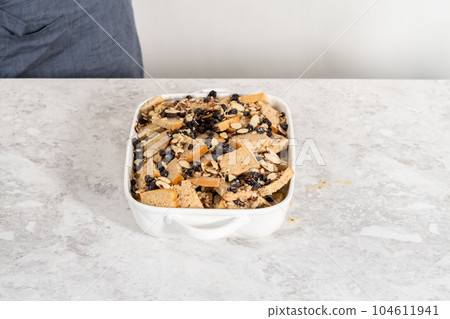 Baking bread pudding with raising and almond slivers in a white casserole dish. Baking bread pudding with raising and almond slivers in a white casserole dish. 104611941
